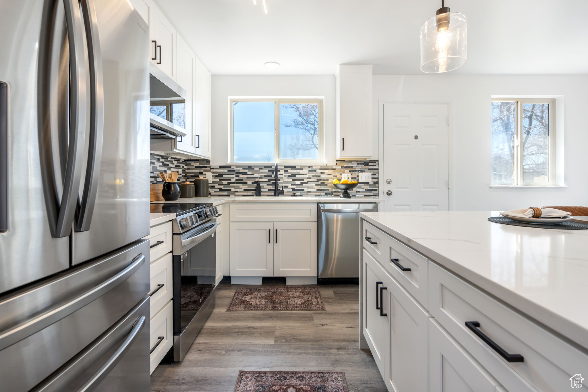 Kitchen with white cabinets, backsplash, dark hardwood / wood-style floors, and stainless steel appliances