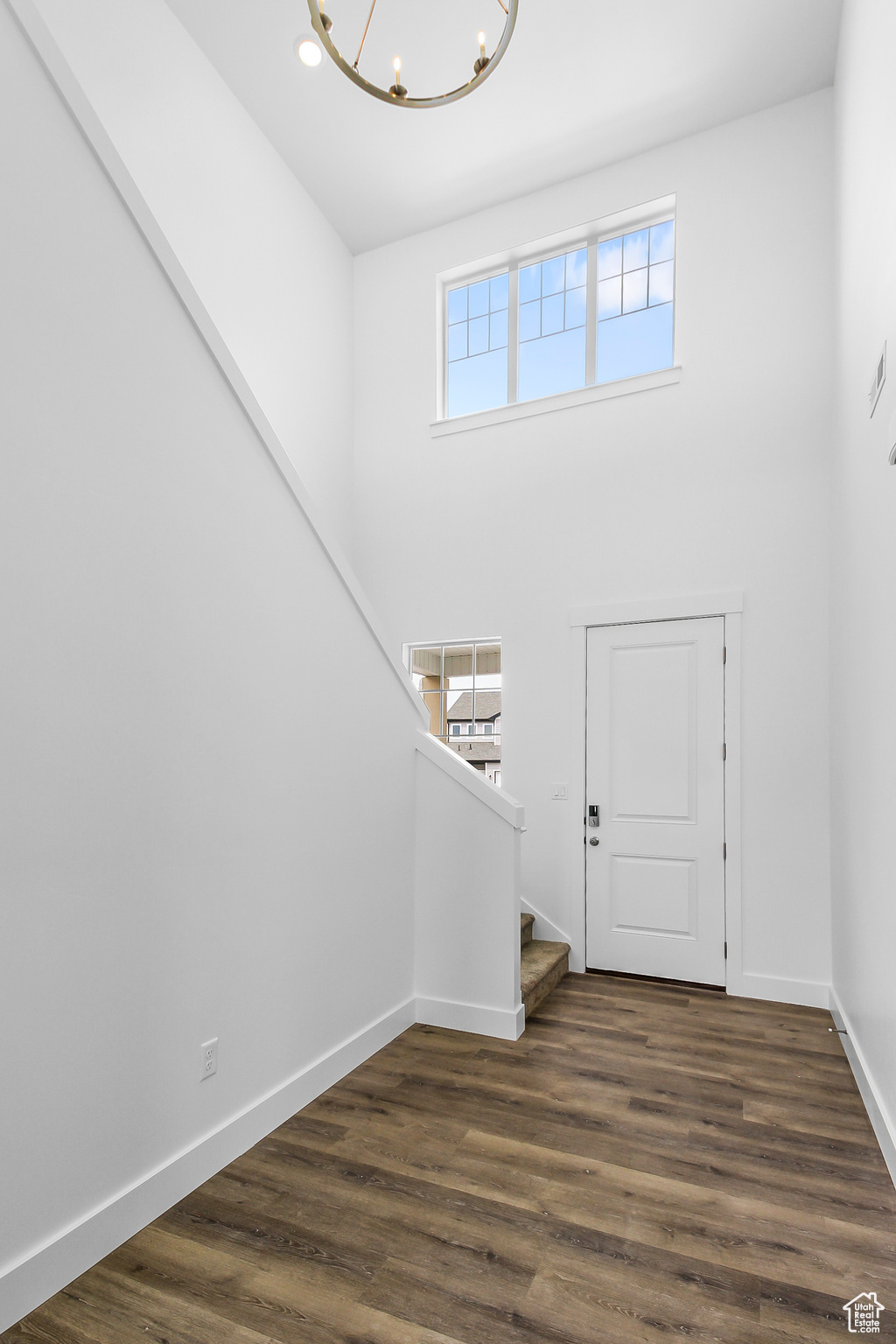 Foyer featuring plenty of natural light, an inviting chandelier, dark hardwood / wood-style flooring, and a high ceiling