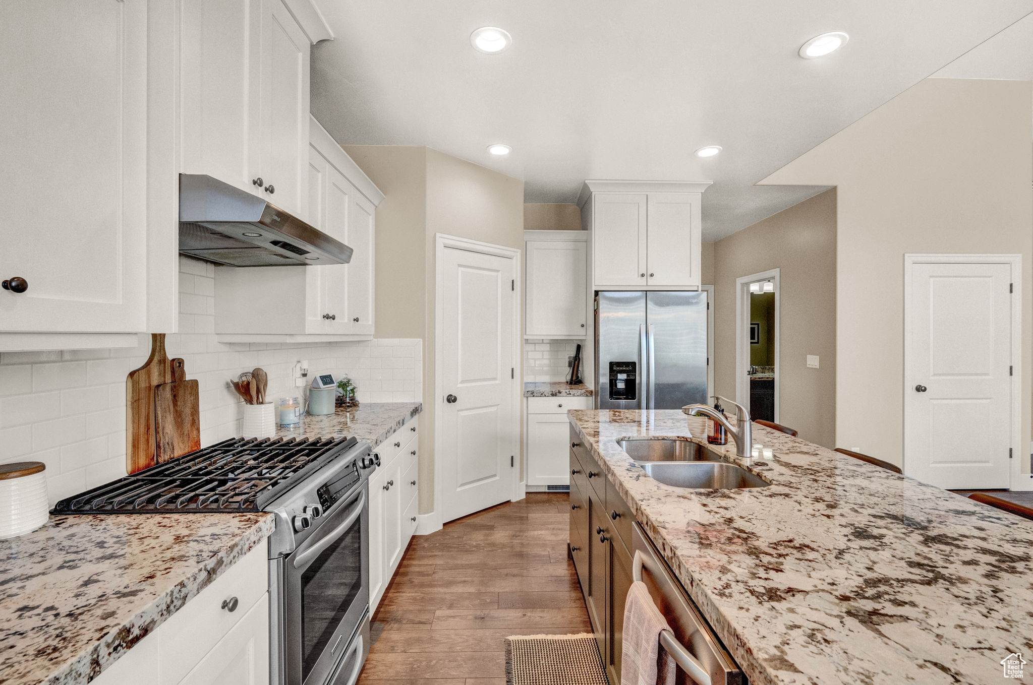 Kitchen featuring white cabinetry, appliances with stainless steel finishes, sink, tasteful backsplash, and hardwood / wood-style flooring