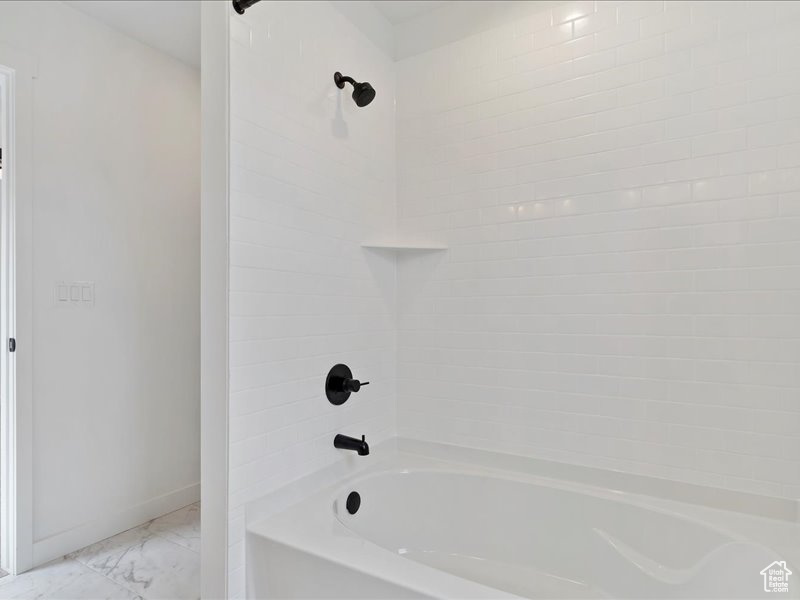 Bathroom featuring tiled shower / bath combo and tile floors