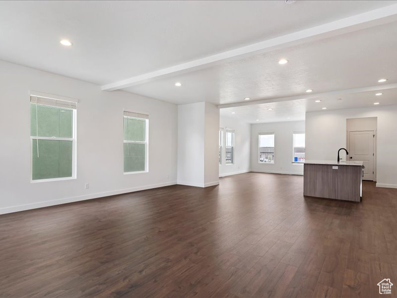 Unfurnished living room featuring dark hardwood / wood-style floors, sink, and beamed ceiling