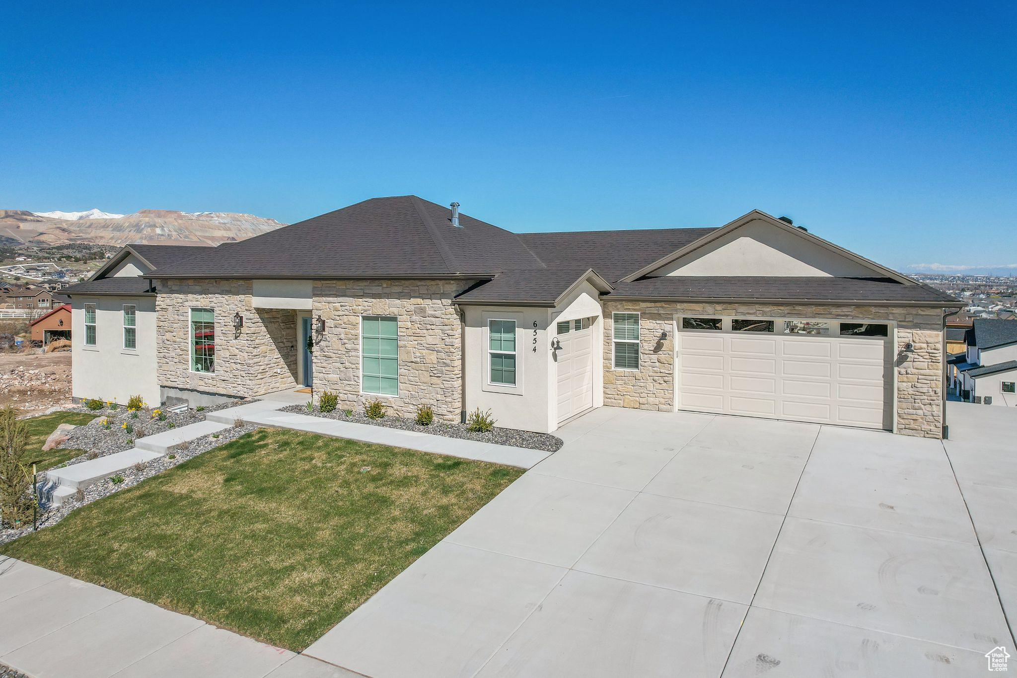 View of front of home featuring a beautifully landscaped lawn, 3 car garage, valley views, & walkout basement
