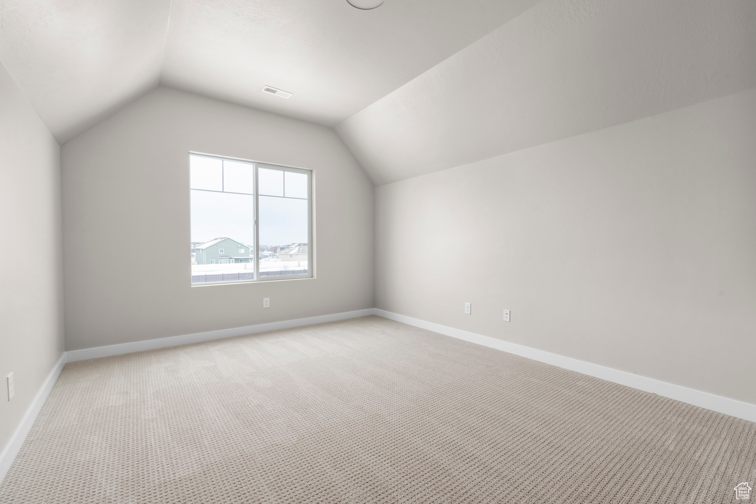 Bonus room with lofted ceiling and light colored carpet