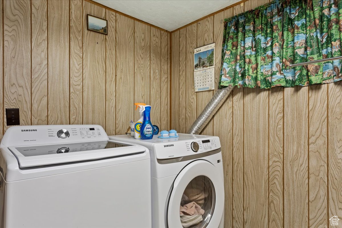 Washroom featuring washing machine and clothes dryer and wooden walls