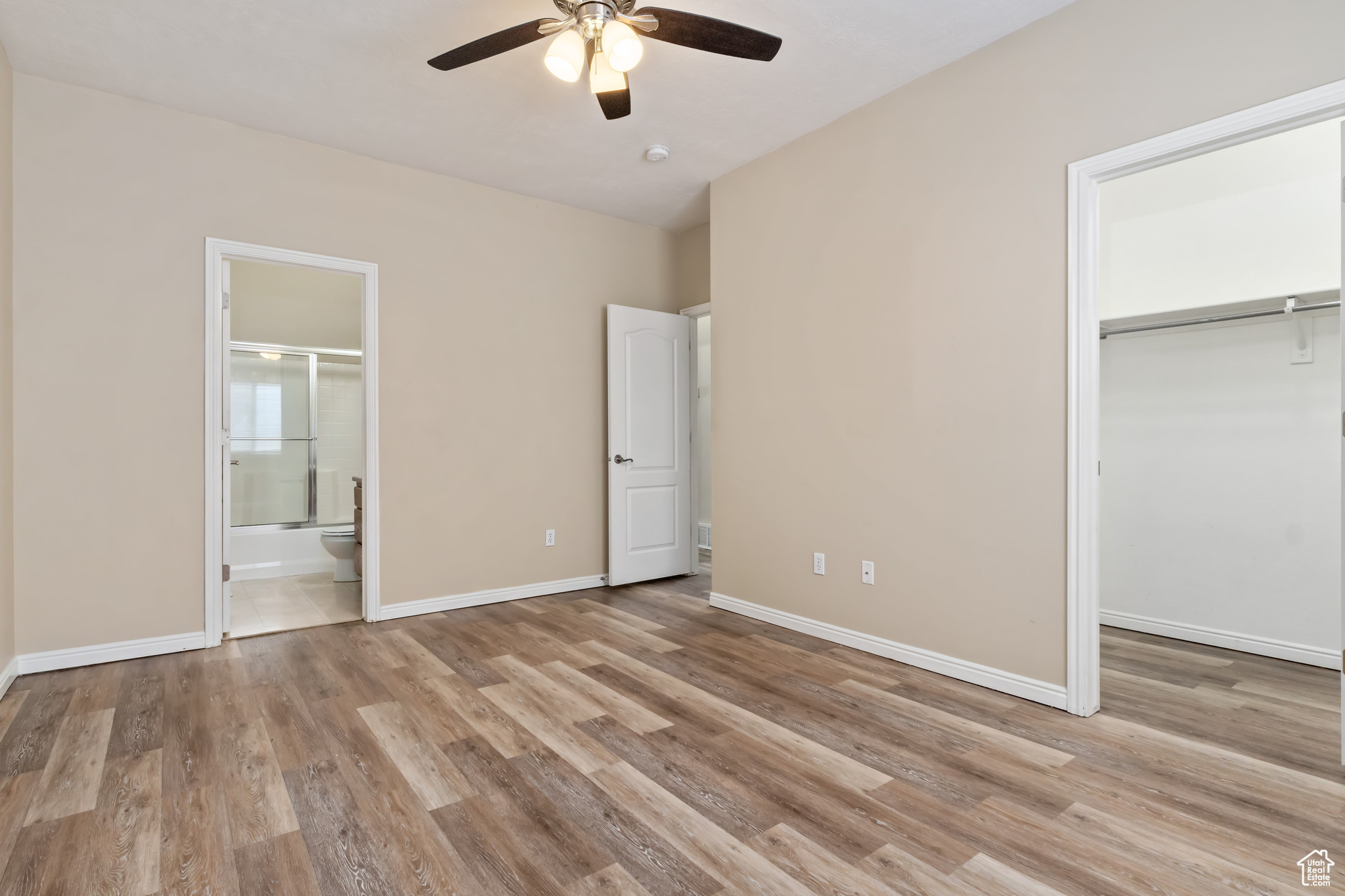 Unfurnished bedroom featuring light hardwood / wood-style floors, connected bathroom, a closet, and ceiling fan