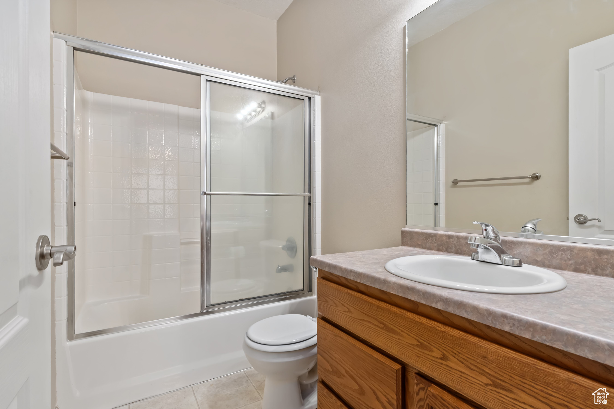 Full bathroom featuring vanity, tile flooring, toilet, and enclosed tub / shower combo