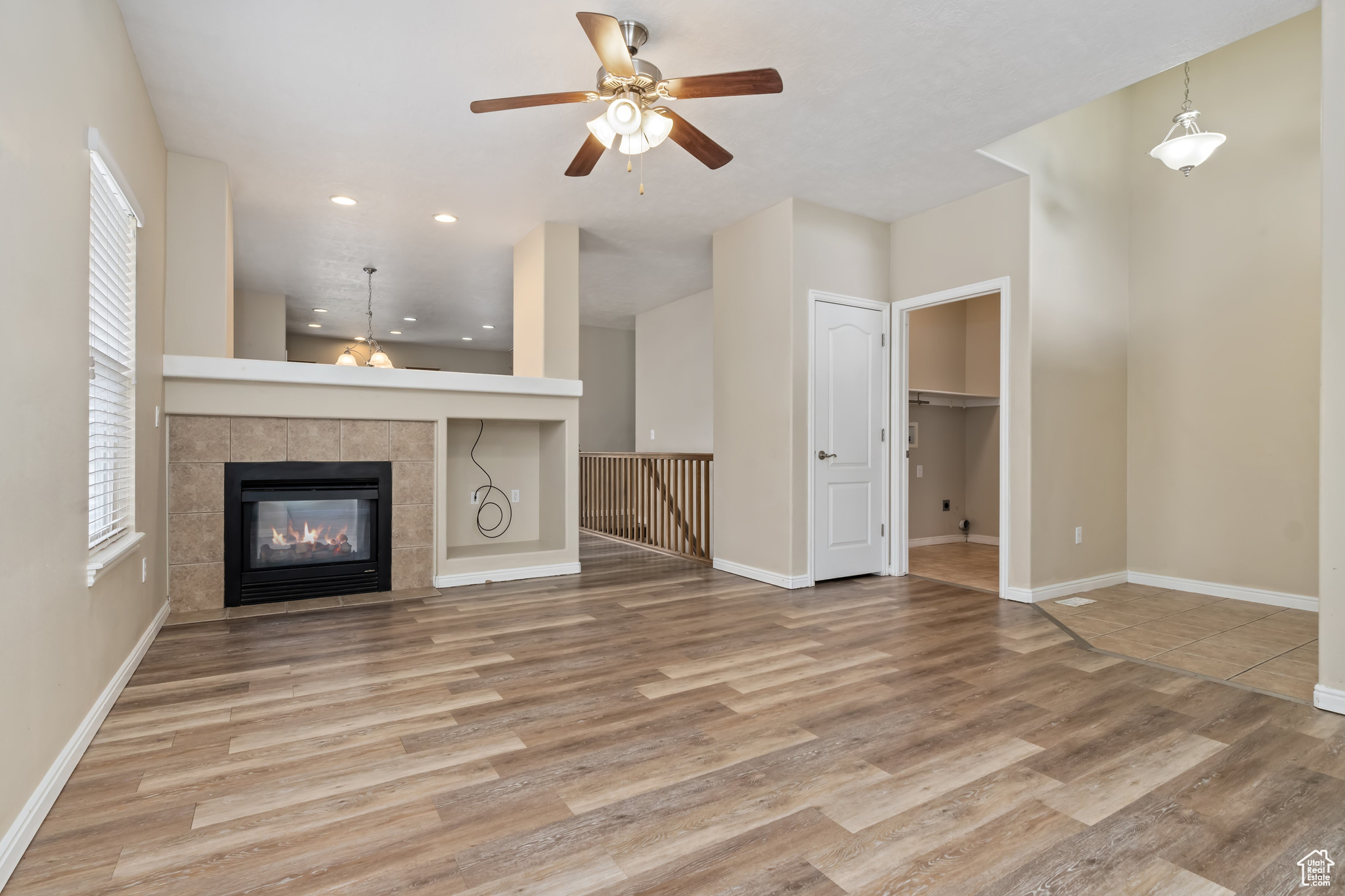 Unfurnished living room featuring light hardwood / wood-style floors, a tiled fireplace, and ceiling fan