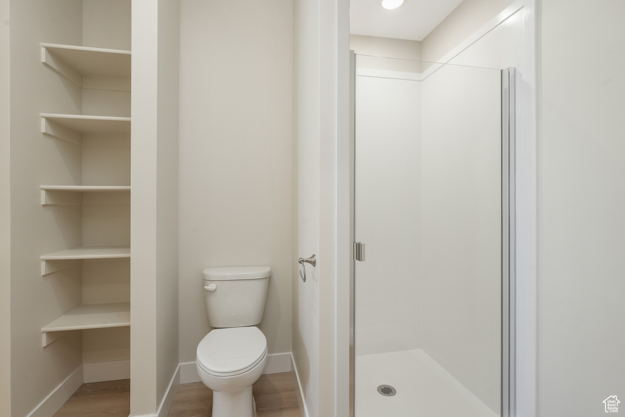 Bathroom with hardwood / wood-style flooring, toilet, and walk in shower