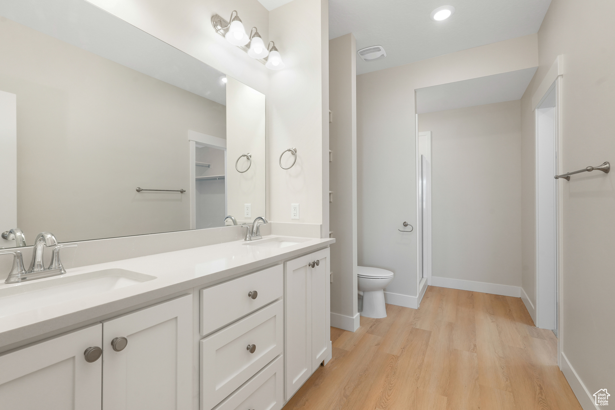 Bathroom featuring hardwood / wood-style floors, dual bowl vanity, and toilet