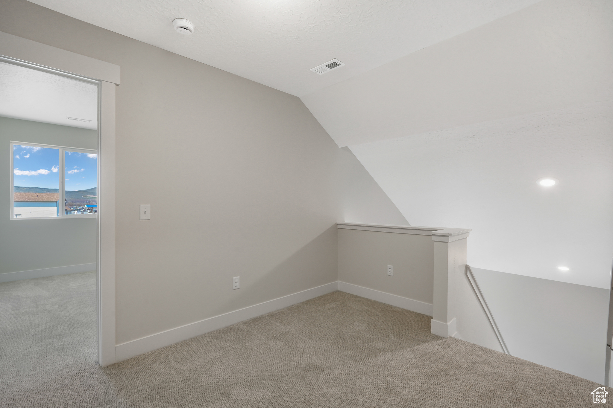 Bonus room with light carpet and vaulted ceiling