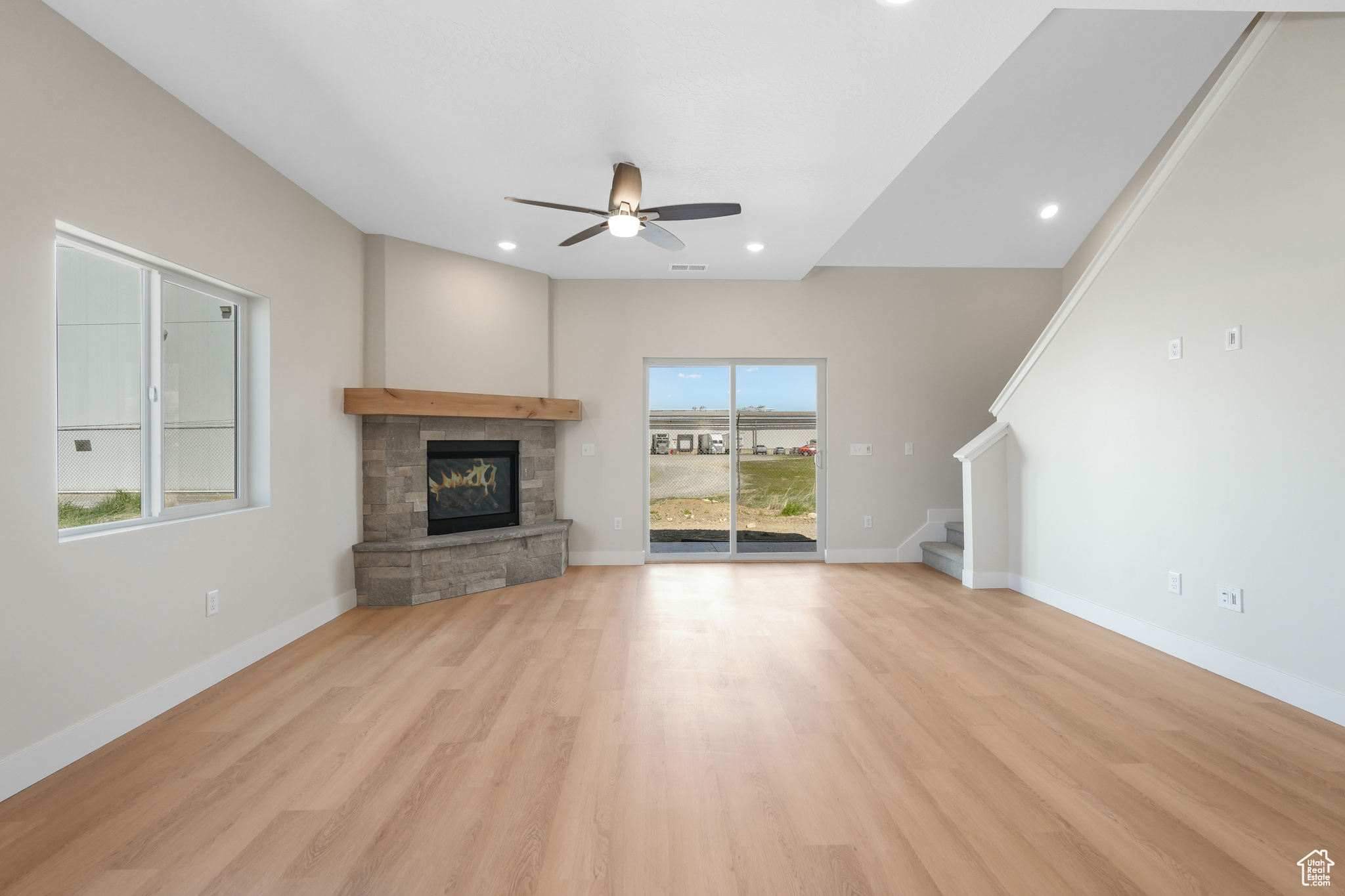 Unfurnished living room featuring plenty of natural light, light hardwood / wood-style floors, ceiling fan, and a fireplace