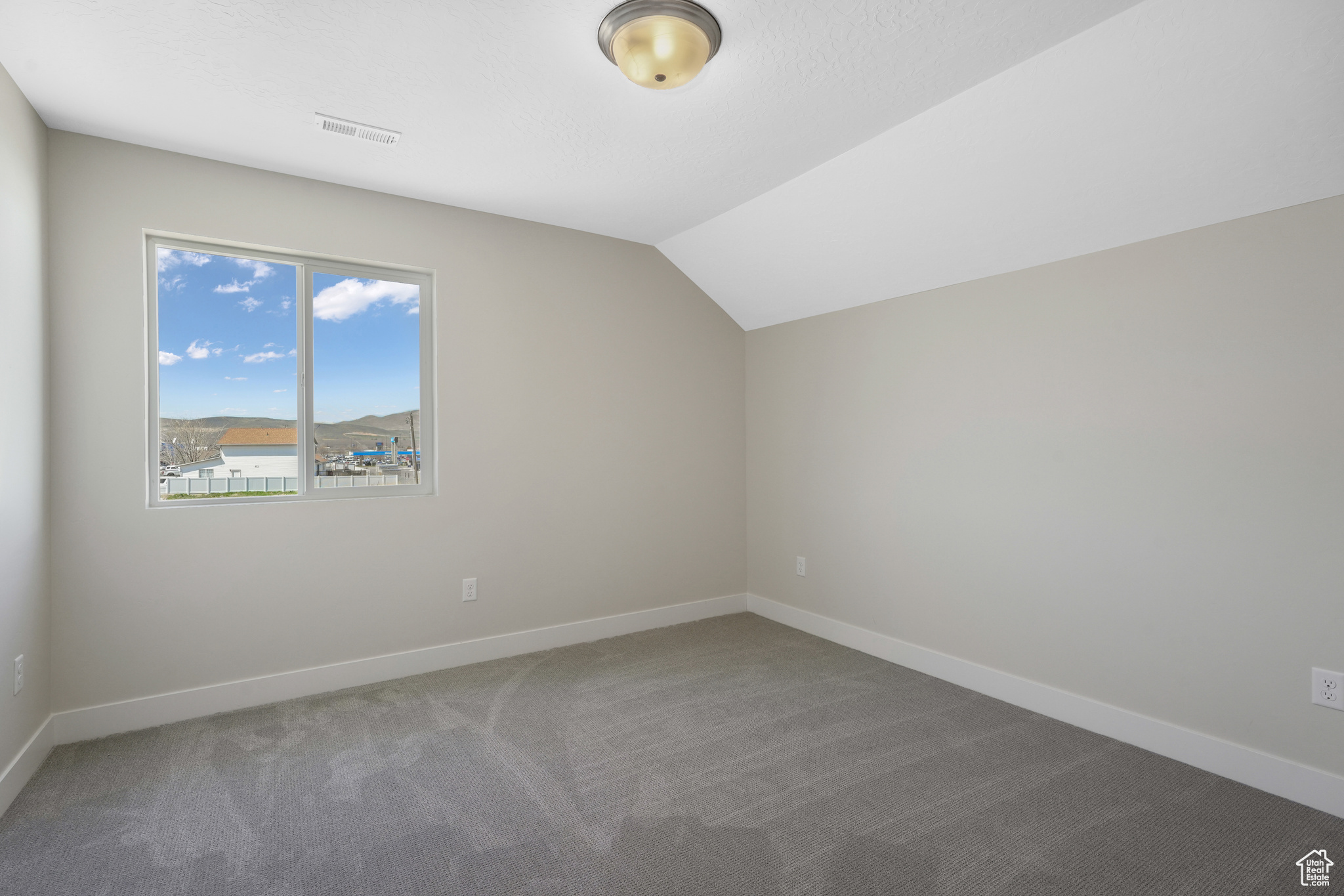 Bonus room with lofted ceiling and dark carpet