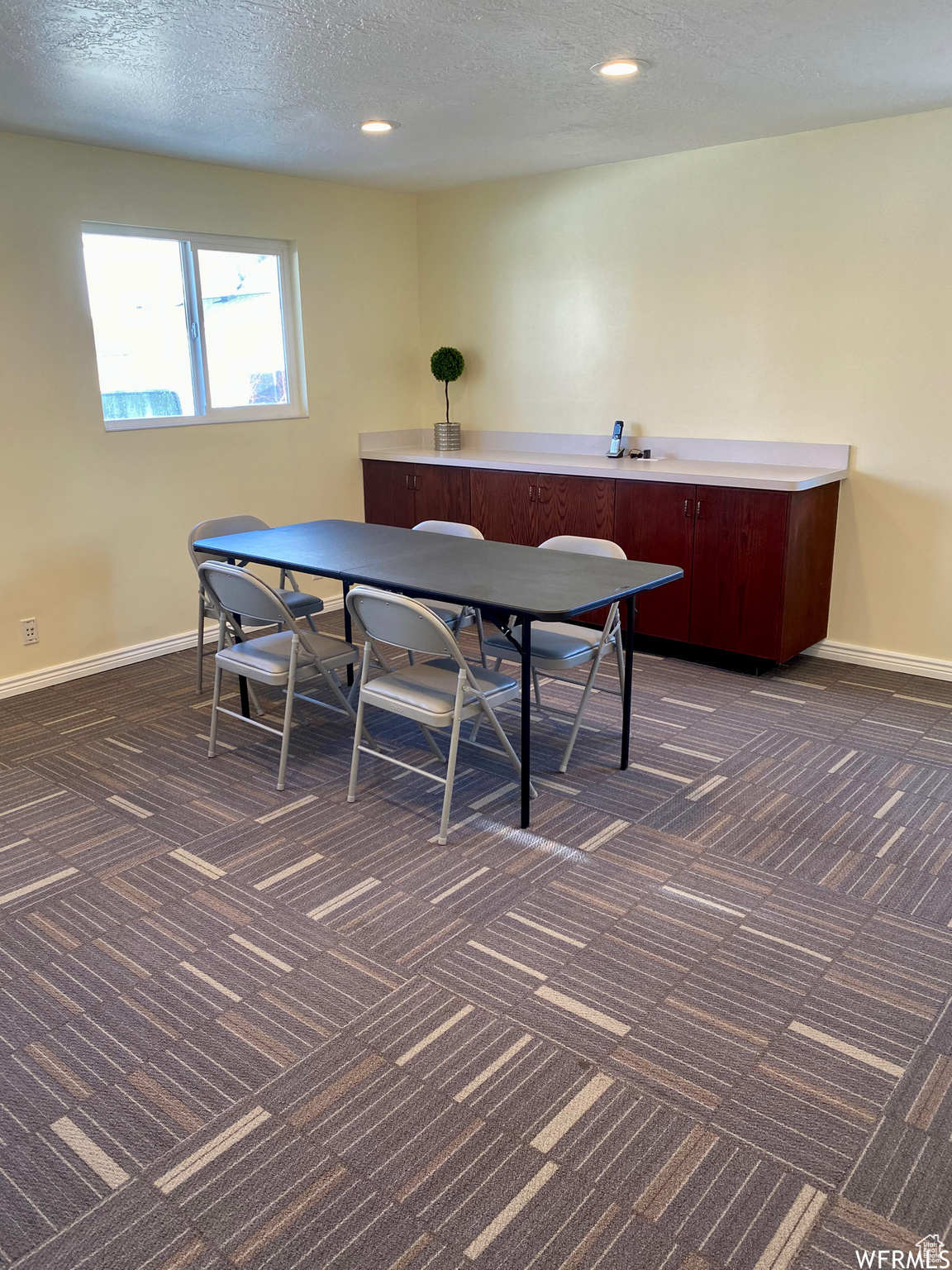 Rec room with dark carpet and a textured ceiling