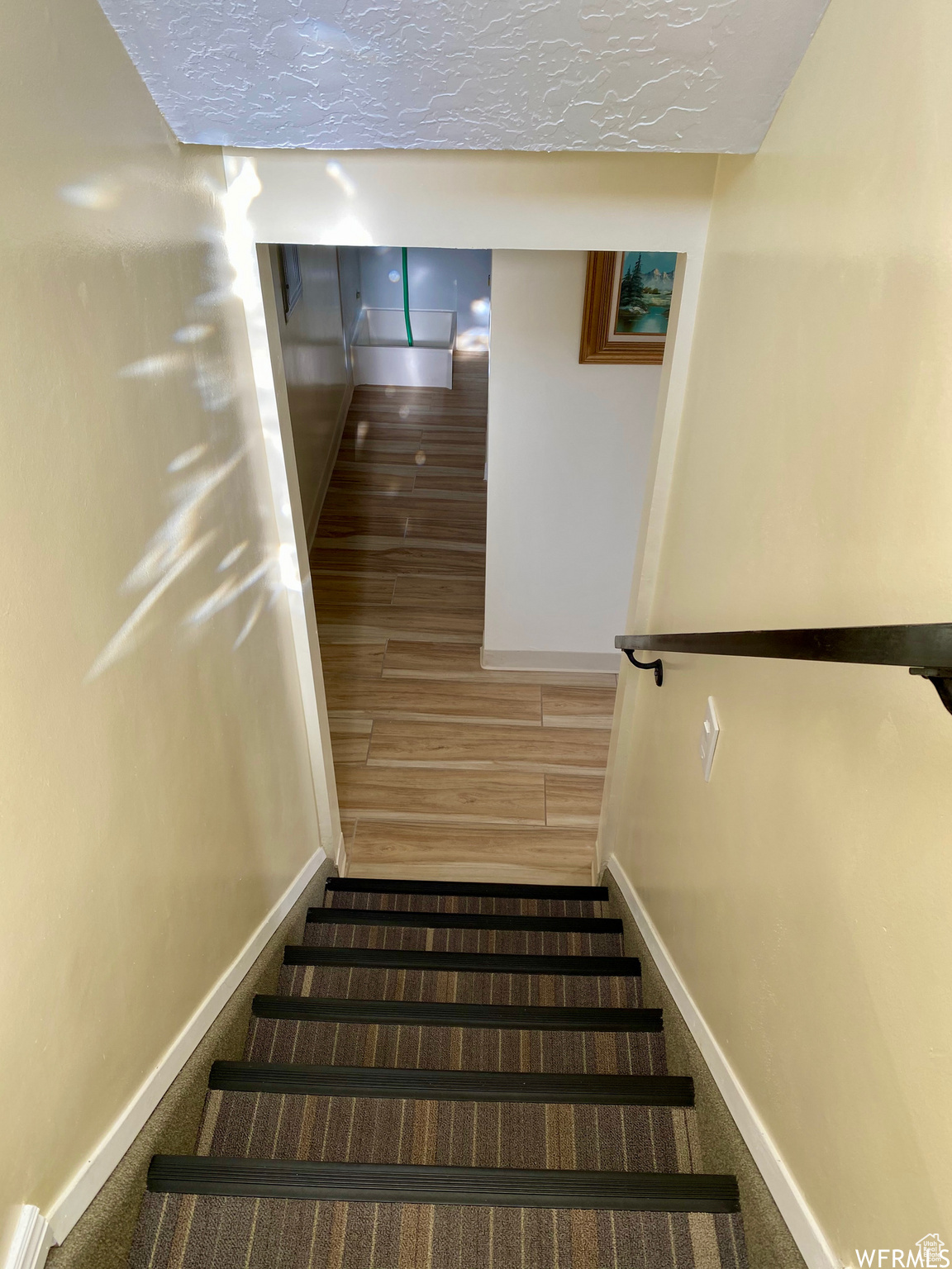 Stairs with a textured ceiling and dark hardwood / wood-style floors