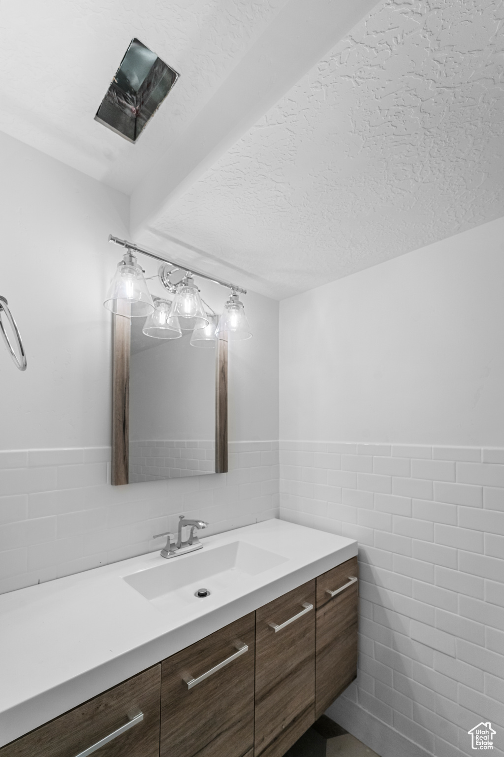Bathroom featuring tile walls, a textured ceiling, and vanity