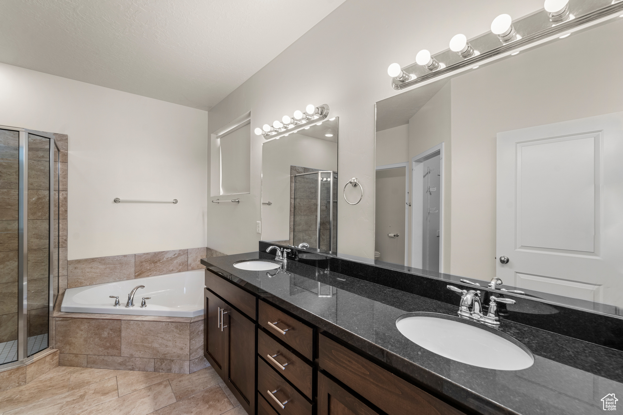 Bathroom featuring tile flooring, dual sinks, separate shower and tub, and oversized vanity
