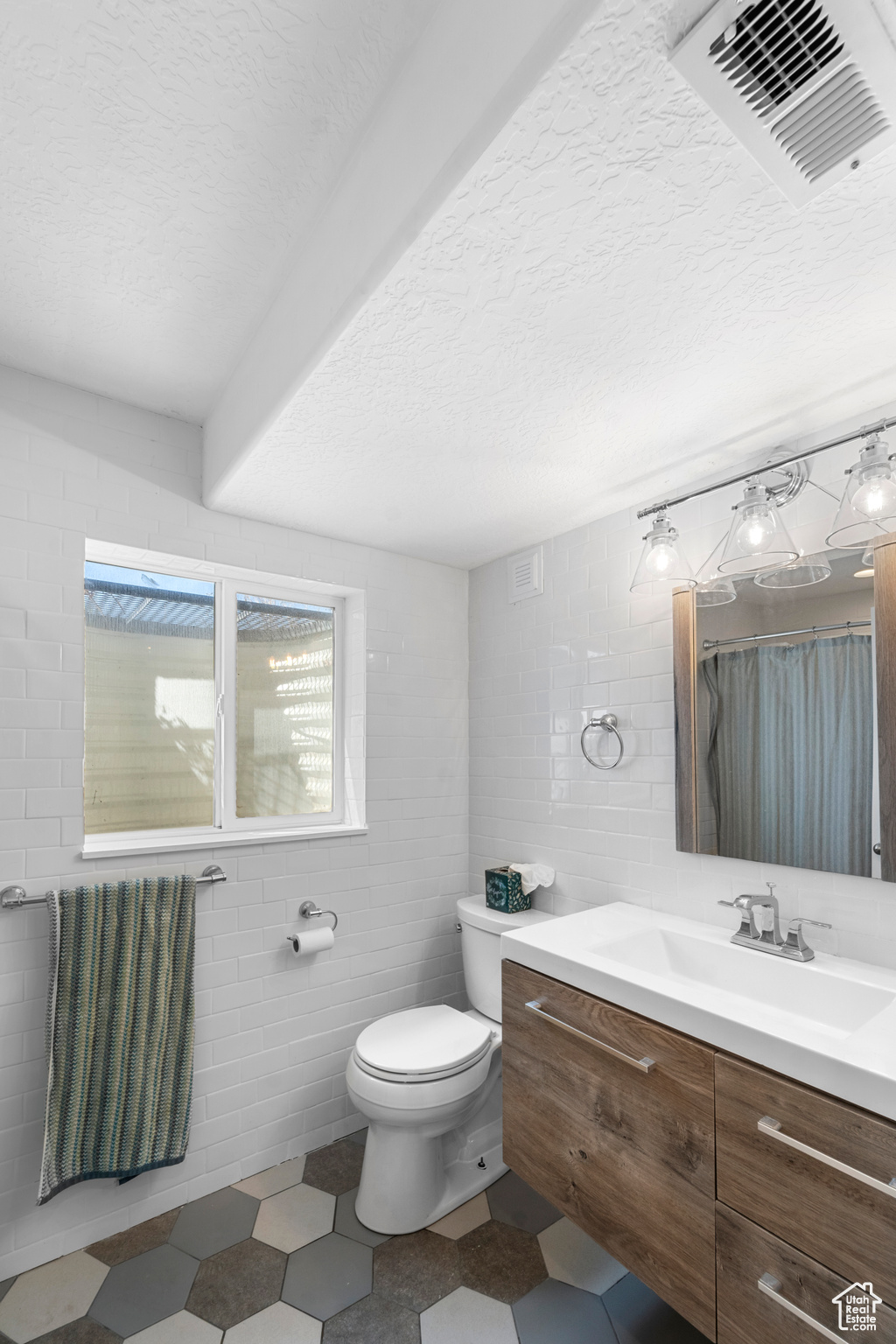 Bathroom featuring tile walls, tile floors, toilet, and vanity