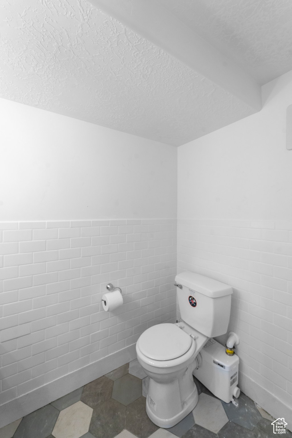 Bathroom with tile flooring, a textured ceiling, tile walls, and toilet