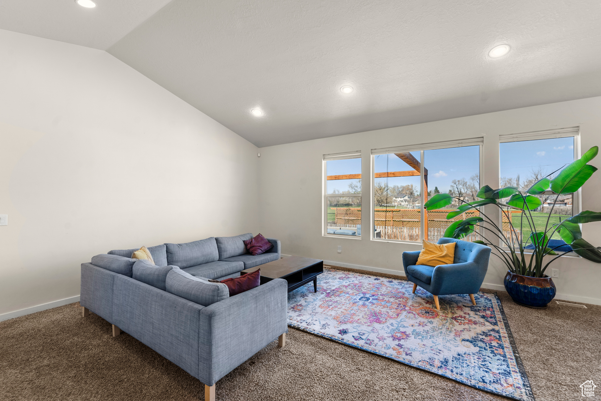 Carpeted living room with lofted ceiling