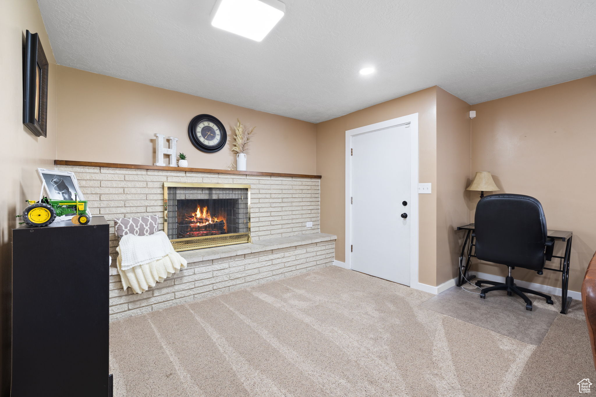 Carpeted office space featuring a brick fireplace