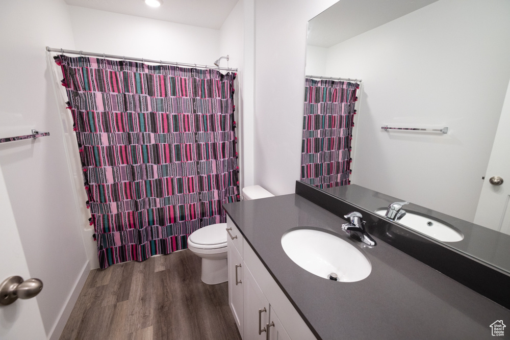 Full bathroom featuring toilet, oversized vanity, and hardwood / wood-style flooring