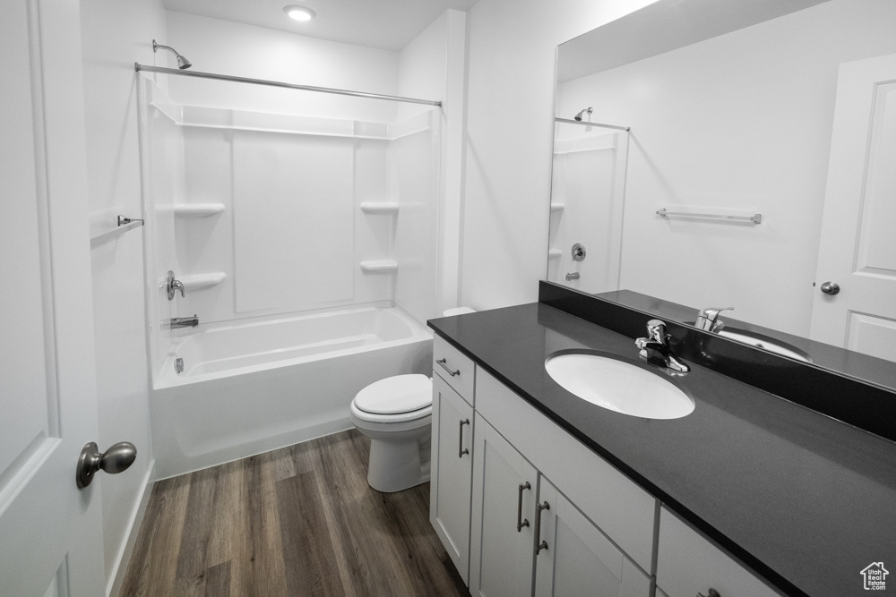 Primary bathroom featuring toilet, oversized vanity, hardwood / wood-style flooring, and tub / shower combination
