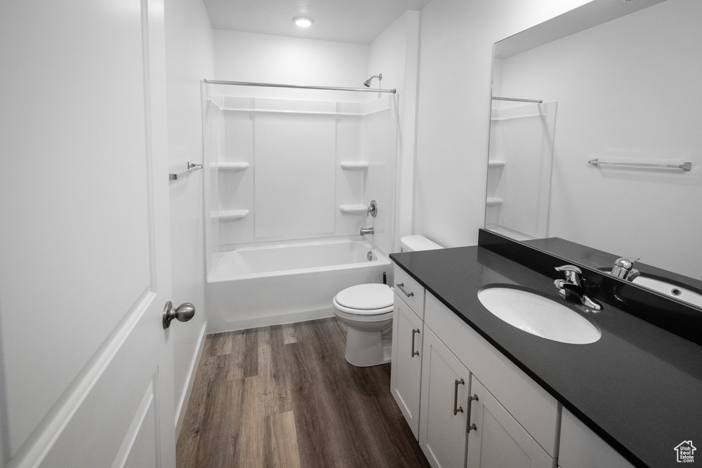 Full bathroom featuring vanity, toilet, tub / shower combination, and hardwood / wood-style floors