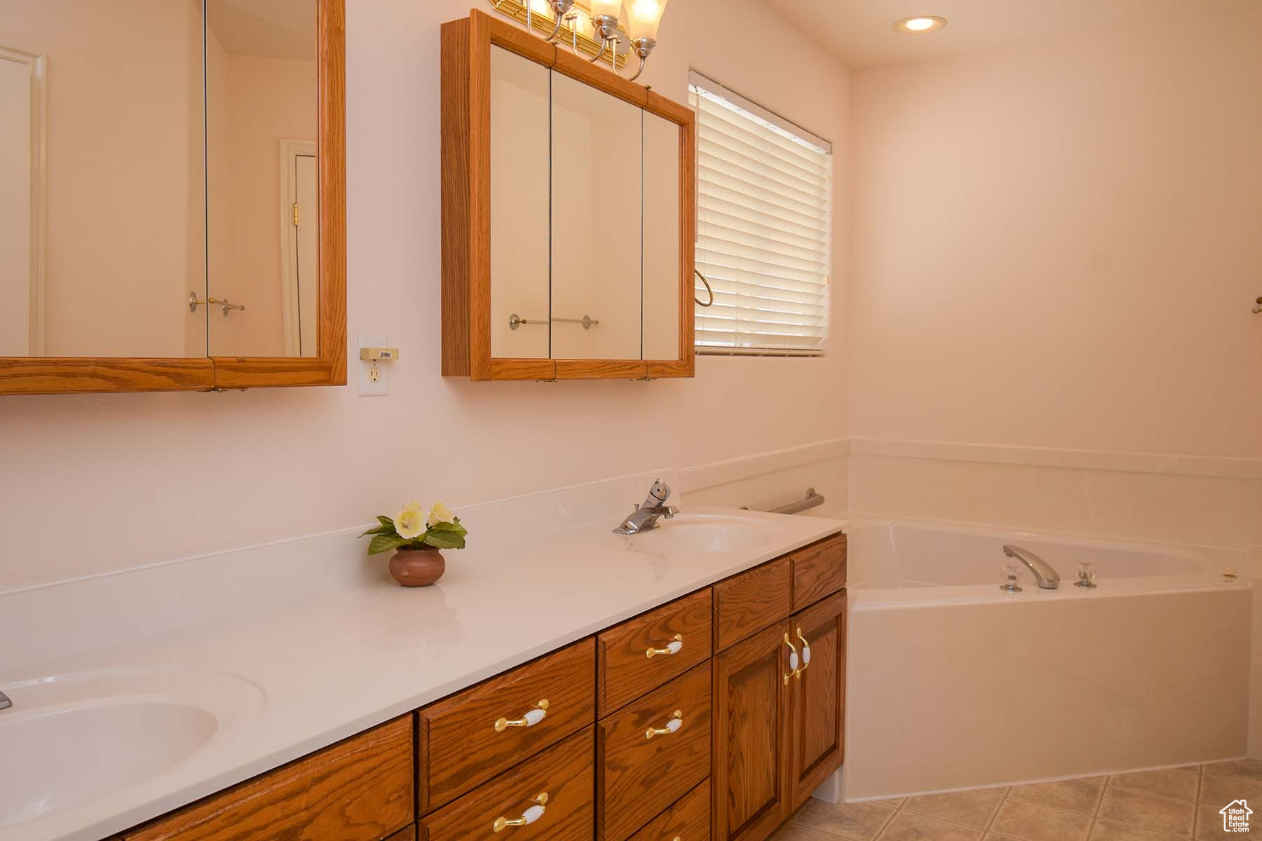 Primary bathroom featuring tile flooring, double sink, vanity with extensive cabinet space, and a bathtub