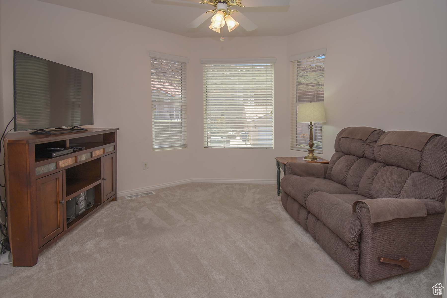 Living area featuring ceiling fan and light colored carpet. Can be a bedroom, office or den