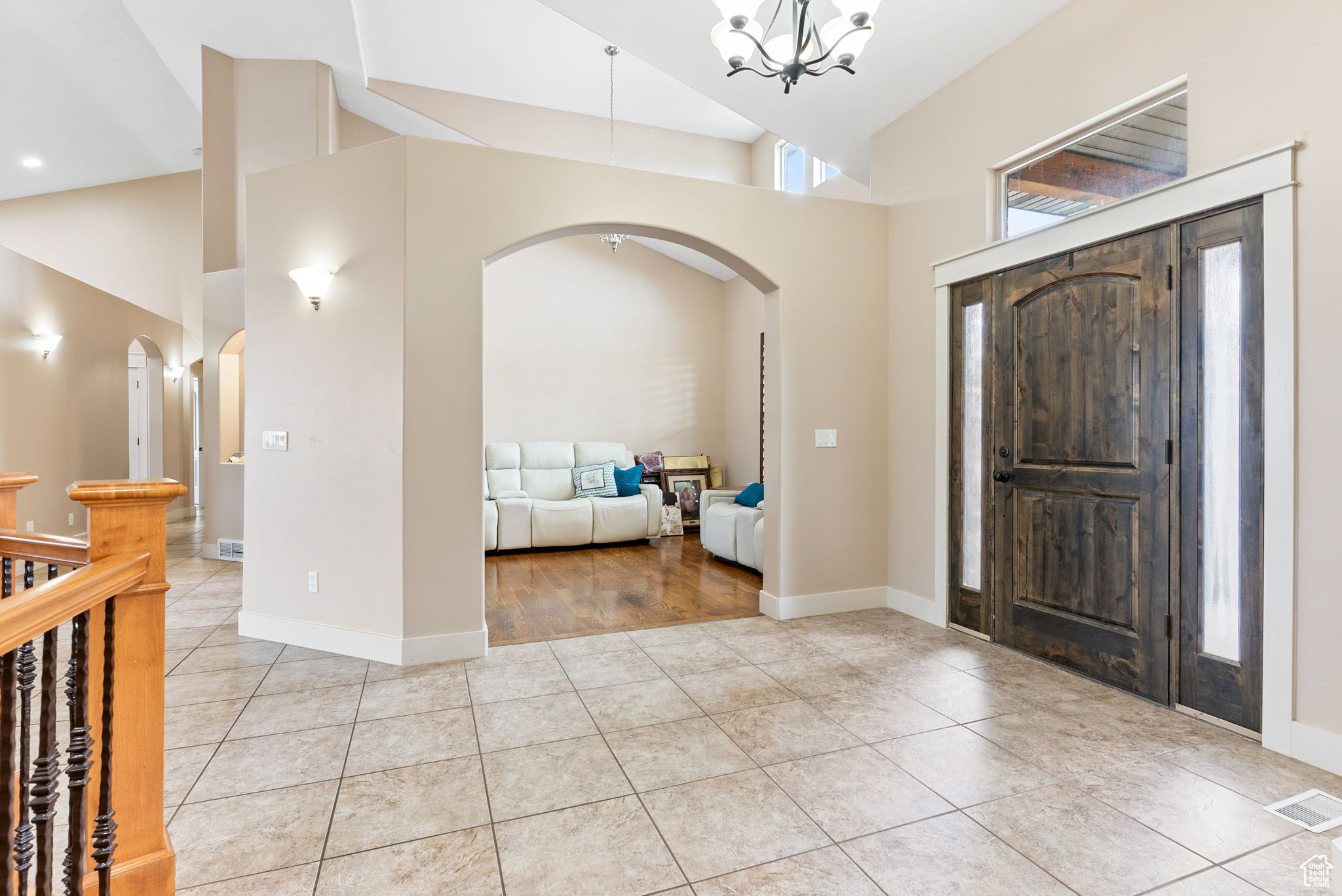 Foyer entrance featuring a notable chandelier, high vaulted ceiling, and light tile floors