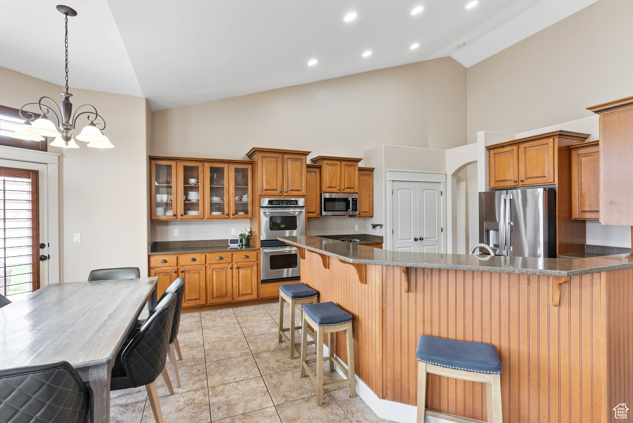 Kitchen featuring an inviting chandelier, a breakfast bar area, light tile floors, stainless steel appliances, and pendant lighting