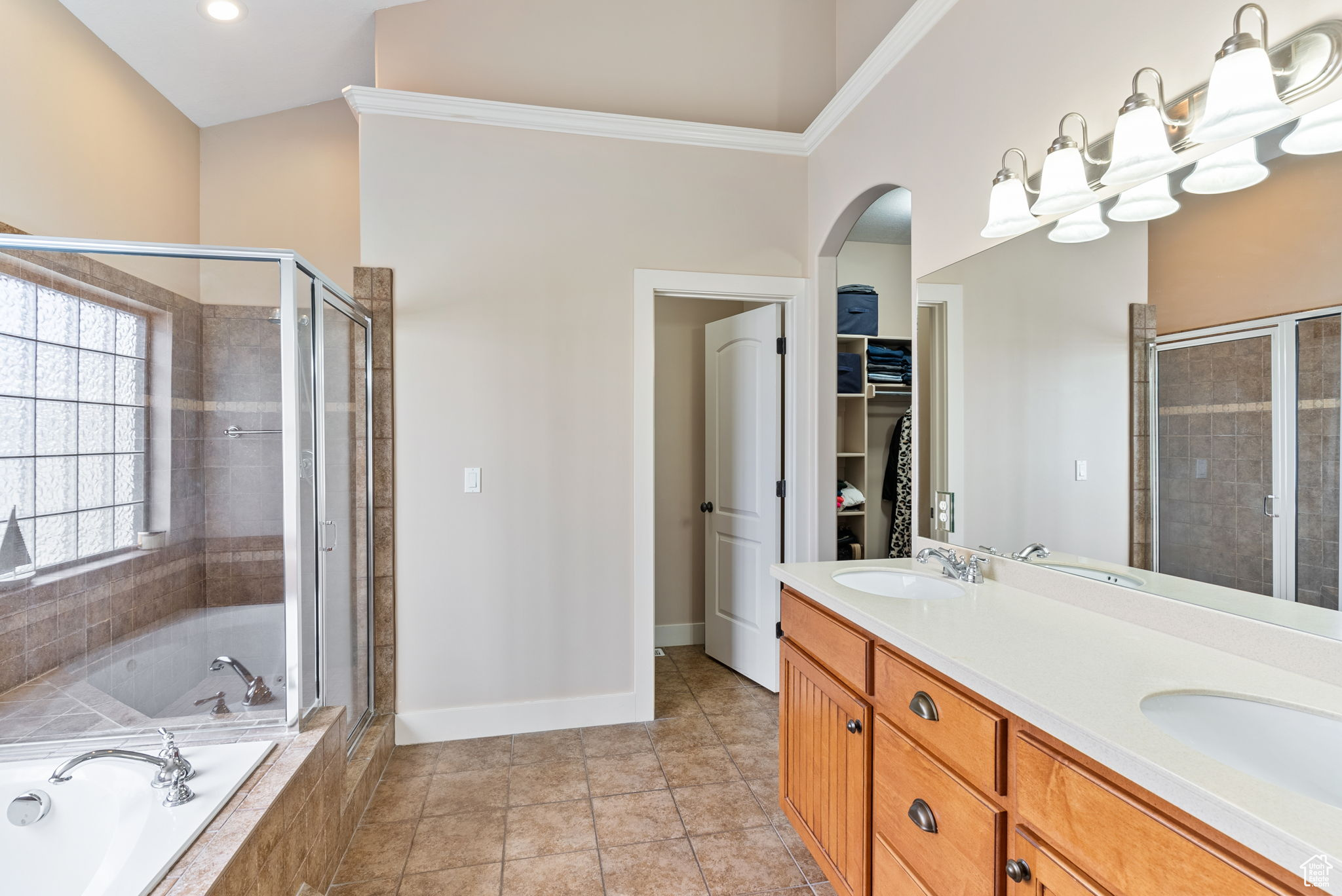 Bathroom featuring crown molding, shower with separate bathtub, dual bowl vanity, and tile flooring