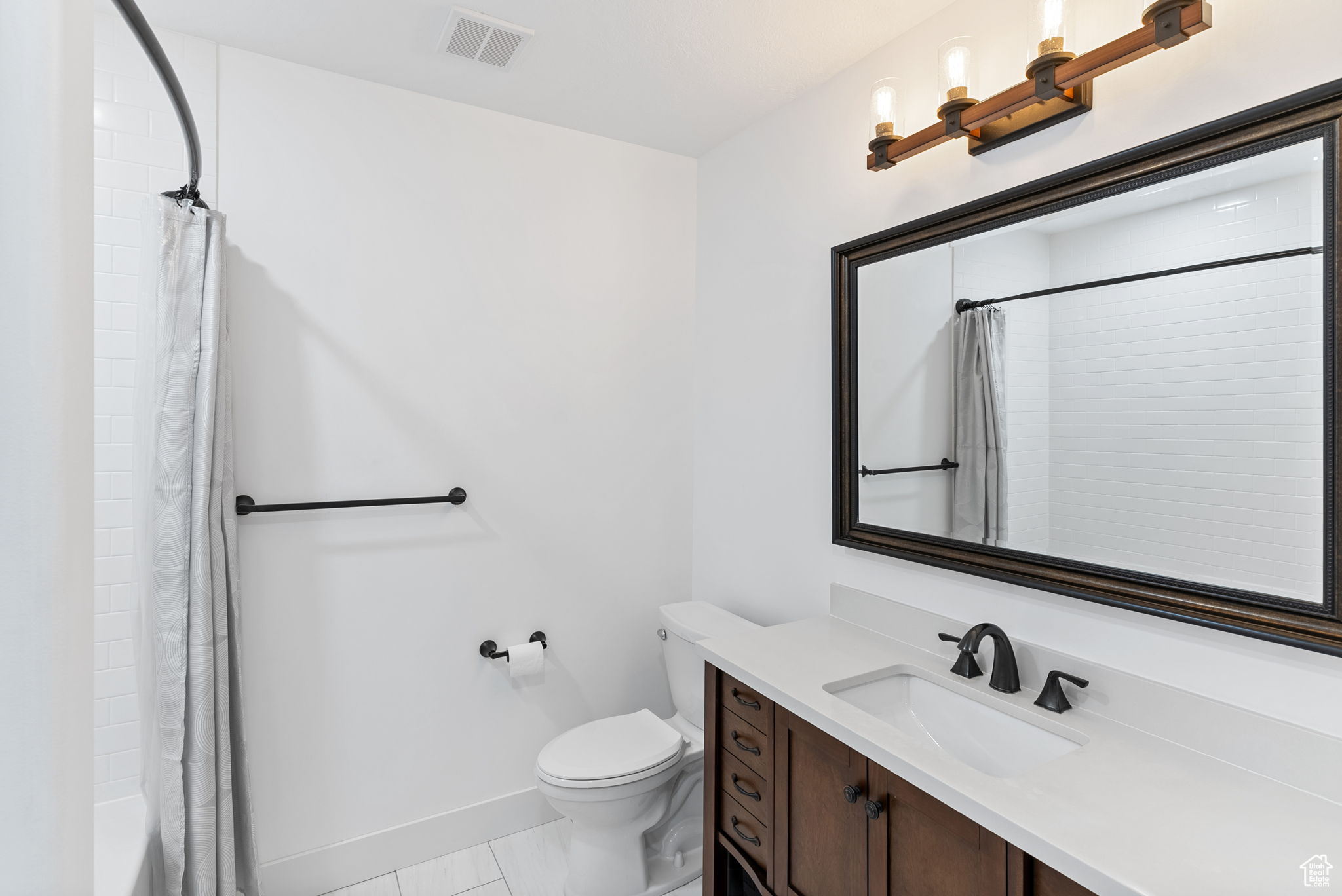 Full bathroom featuring toilet, shower / tub combo with curtain, tile flooring, and vanity with extensive cabinet space