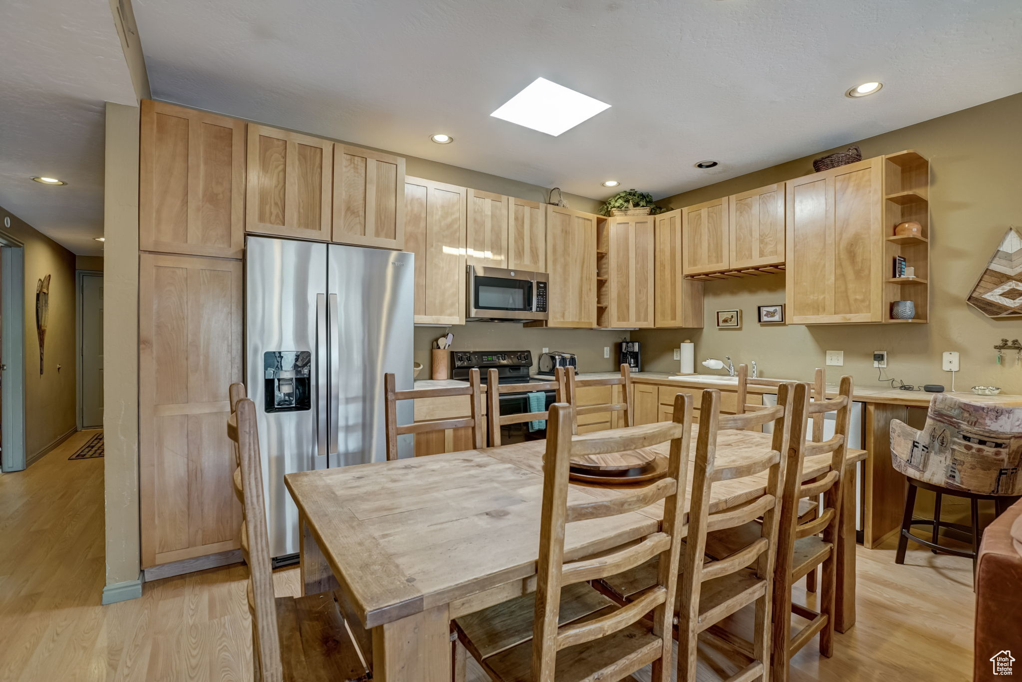 Kitchen featuring light brown cabinets, stainless steel appliances, sink, and light hardwood / wood-style flooring
