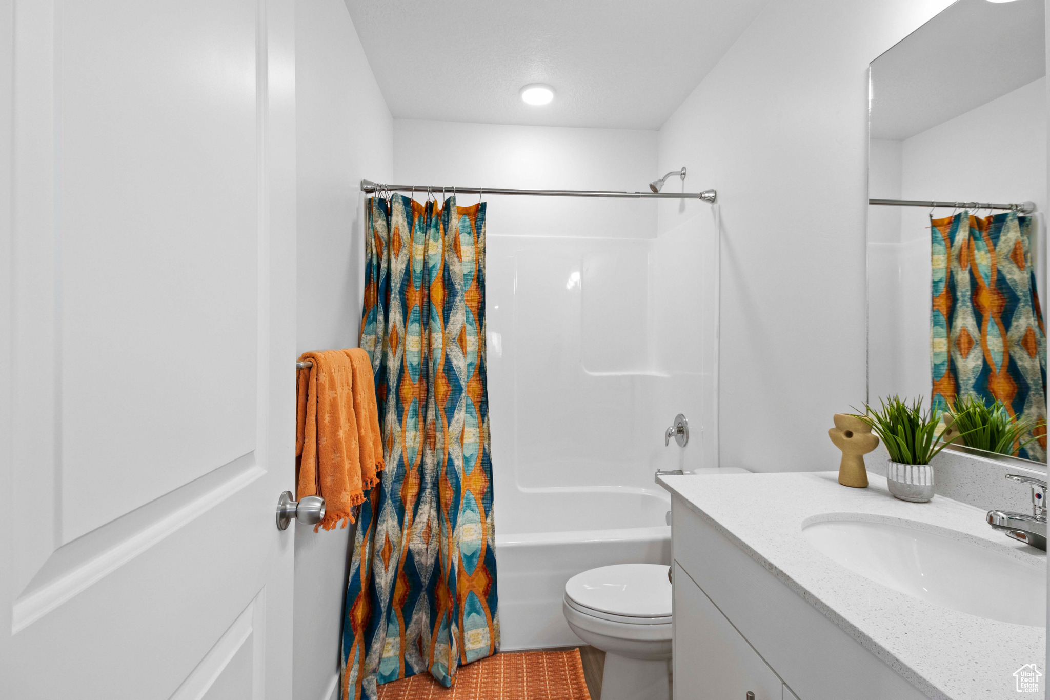 Full bathroom featuring tile floors, toilet, shower / bath combo with shower curtain, and vanity