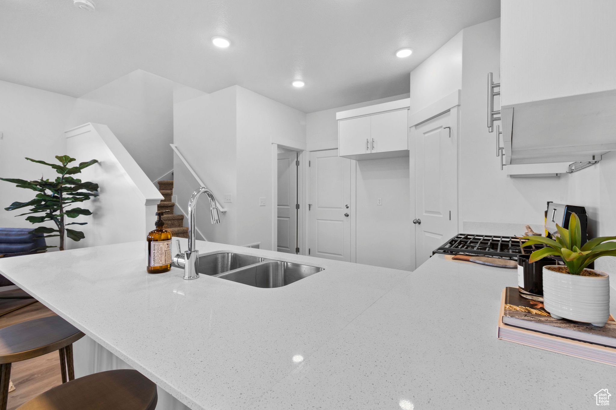 Kitchen with a breakfast bar area, sink, kitchen peninsula, light stone countertops, and white cabinets
