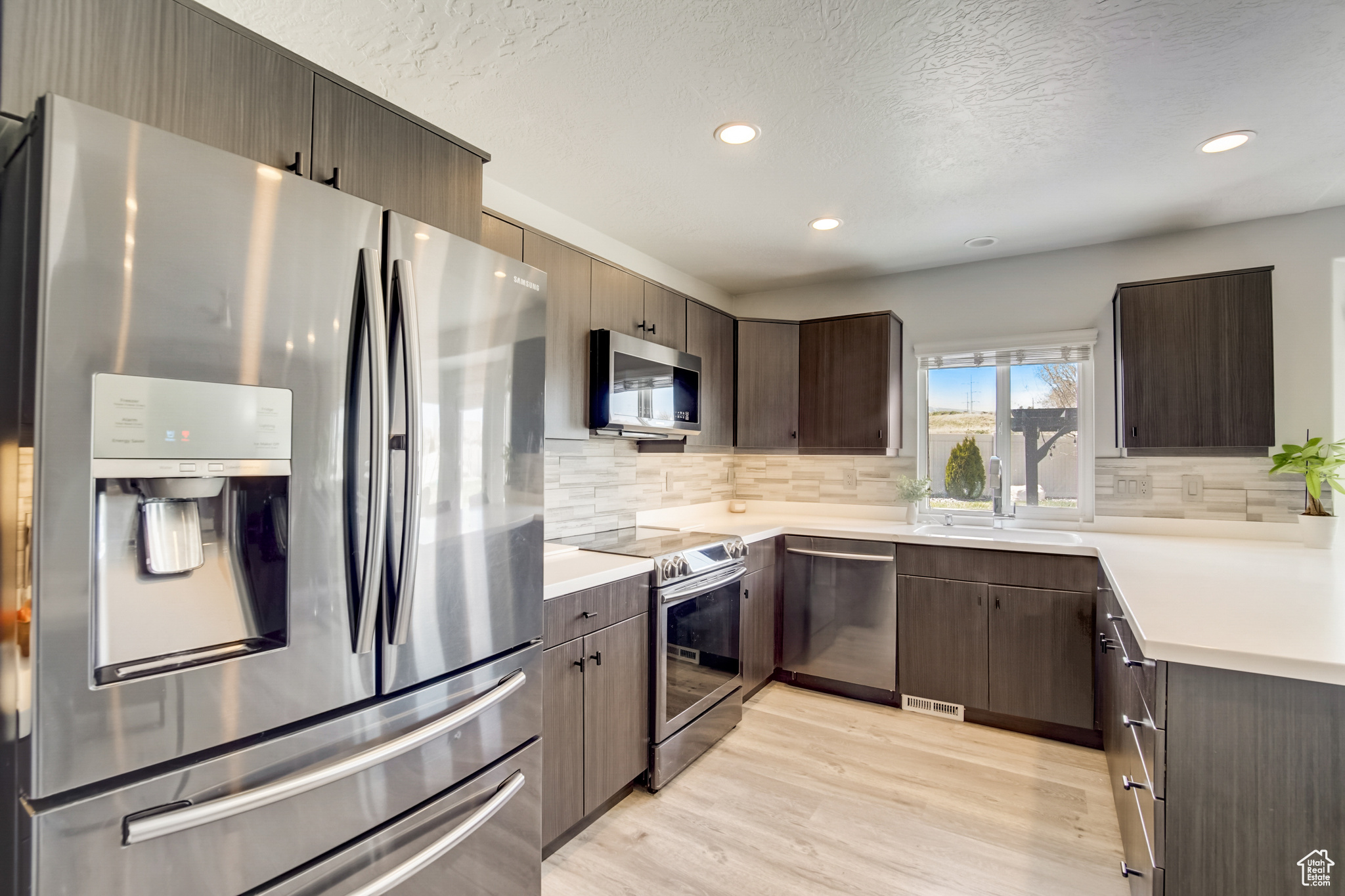 Kitchen featuring appliances with stainless steel finishes, tasteful backsplash, light hardwood / wood-style floors, and sink
