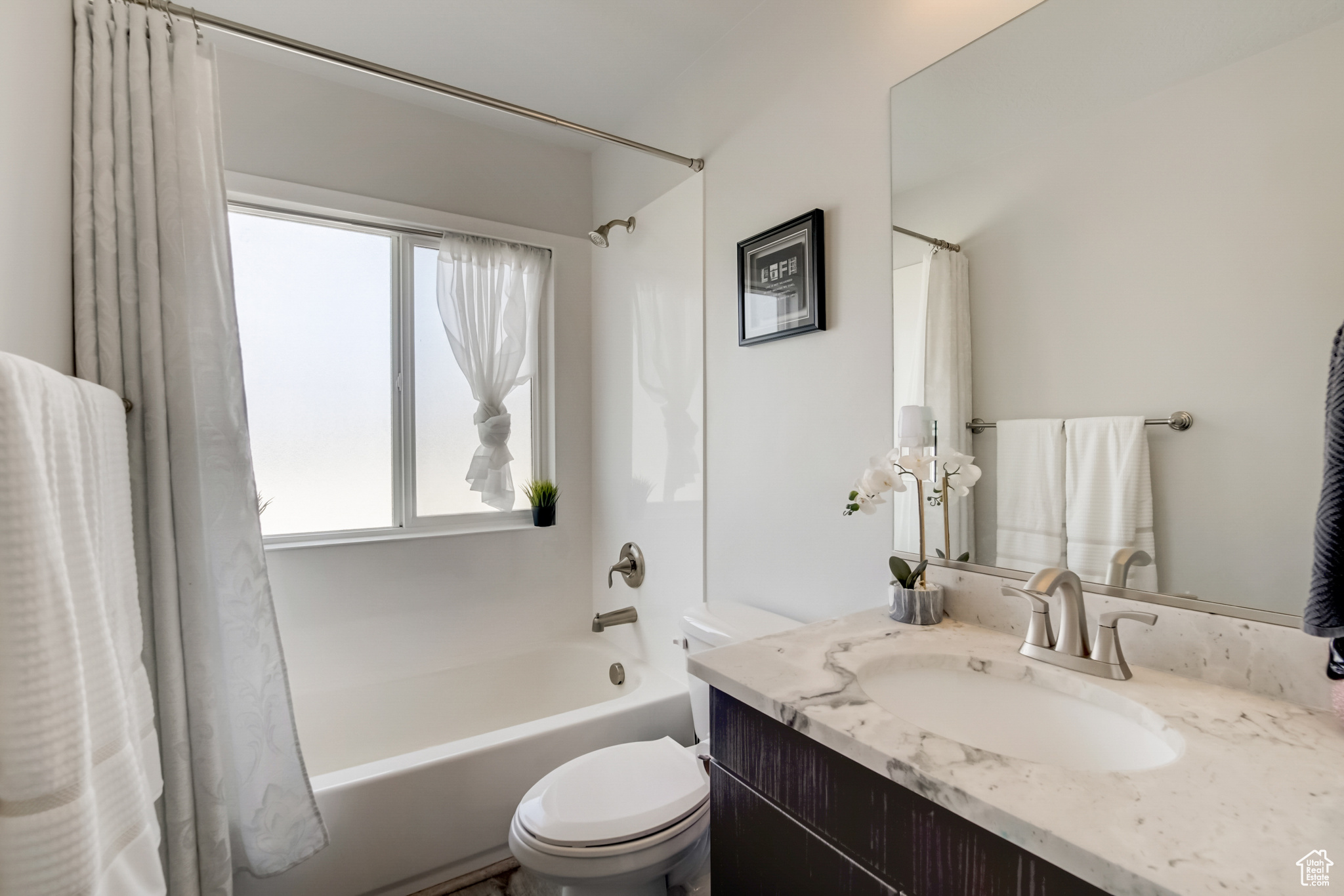 Full bathroom featuring shower / tub combo with curtain, toilet, vanity, and plenty of natural light