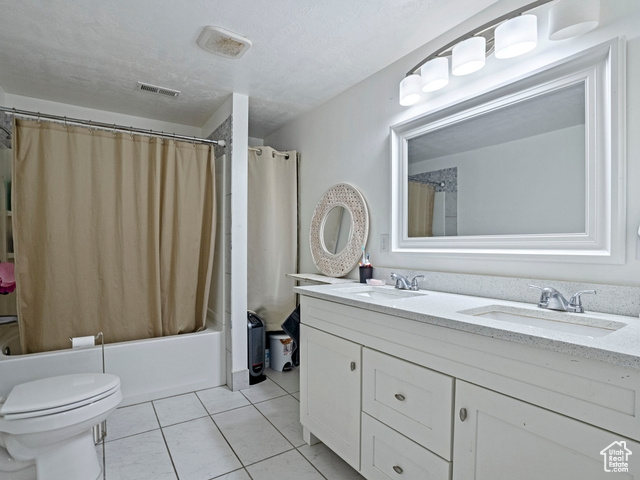 Full bathroom with shower / bath combination with curtain, tile floors, toilet, and double vanity