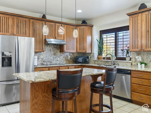 Kitchen with backsplash, light tile floors, decorative light fixtures, and black appliances