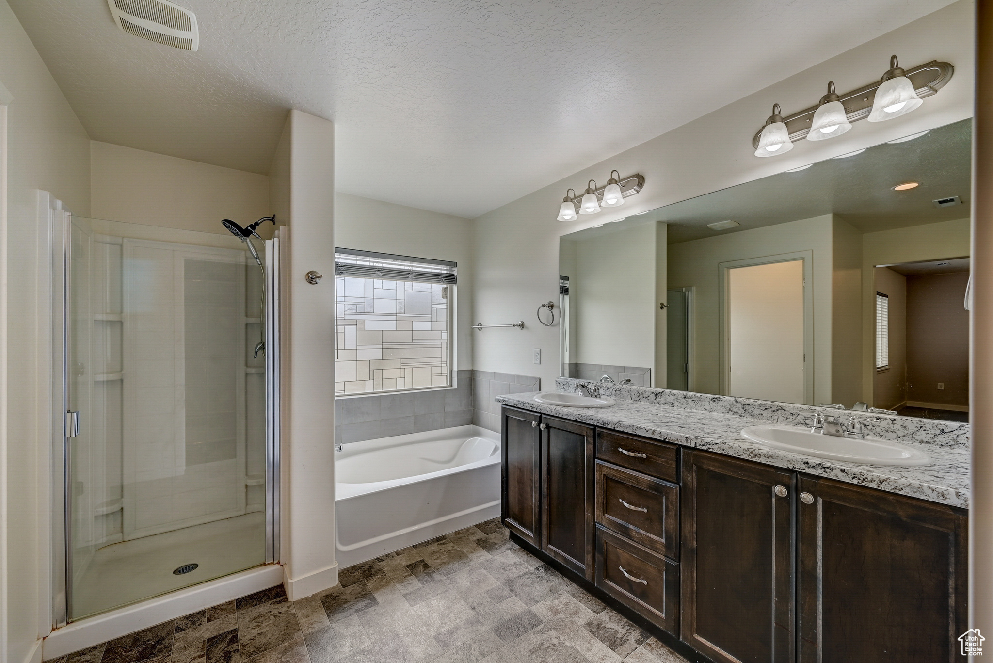 Bathroom with dual sinks, independent shower and bath, a textured ceiling, large vanity,