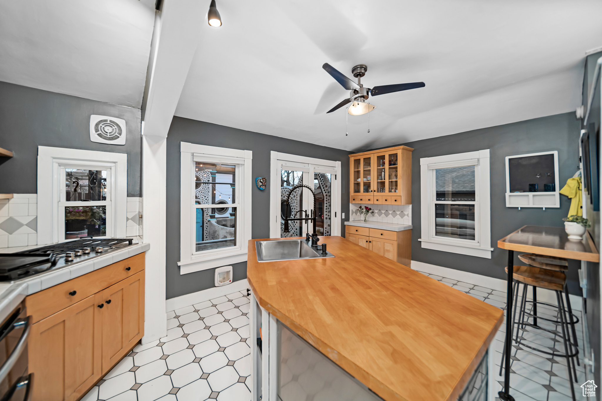 Kitchen with sink, ceiling fan, light tile floors, and tasteful backsplash