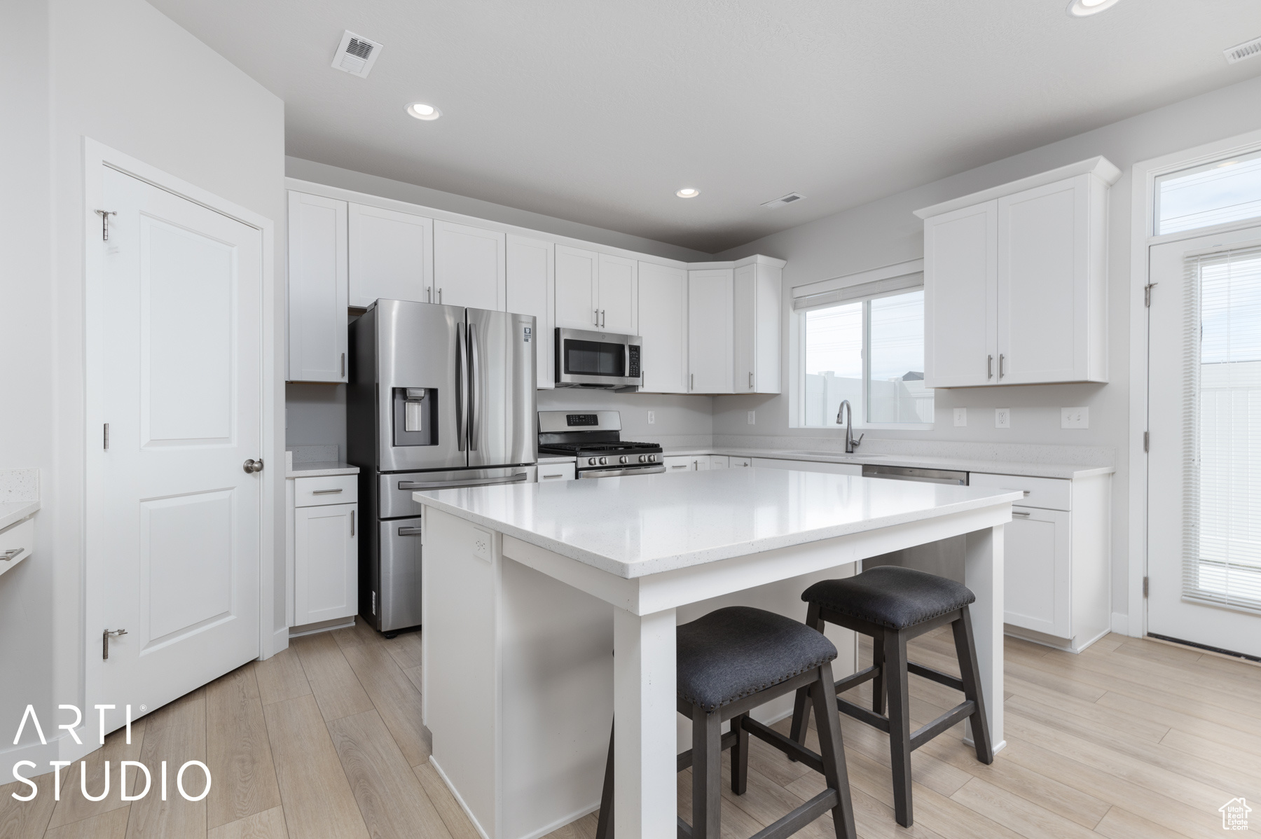 Kitchen featuring appliances with stainless steel finishes, white cabinetry, a kitchen island, and a healthy amount of sunlight