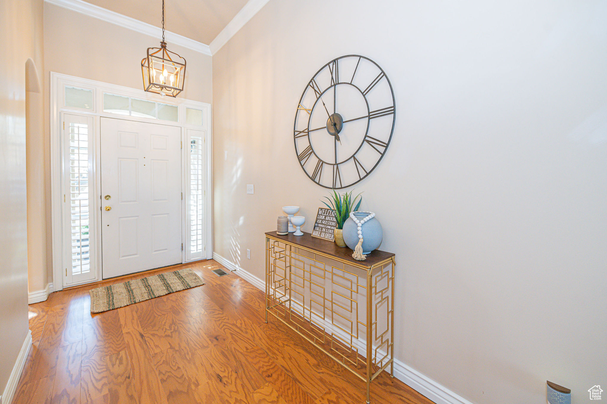 Entrance foyer with crown molding, an inviting chandelier, and hardwood / wood-style floors