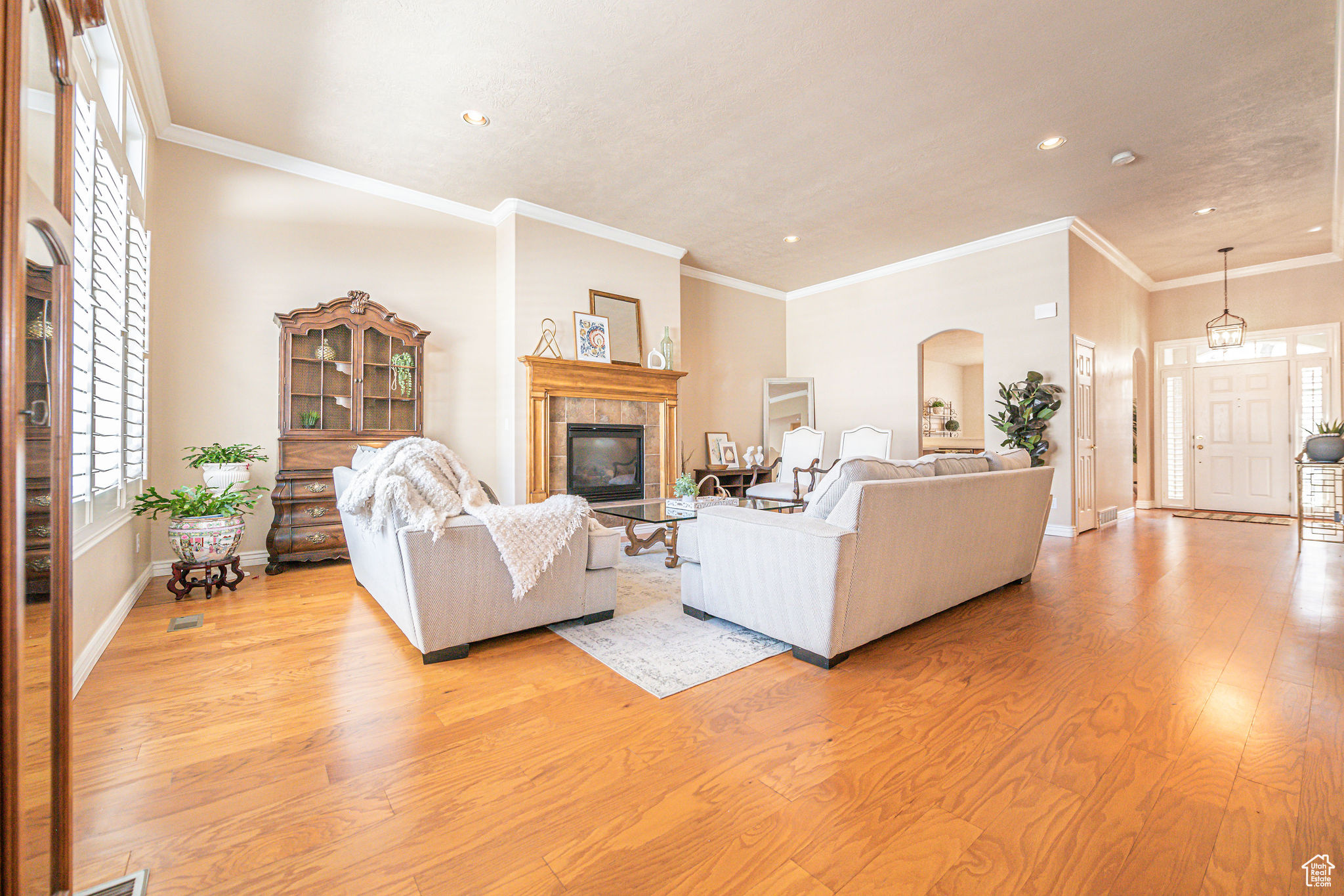 Living room featuring light hardwood / wood-style flooring, crown molding, and a tile fireplace