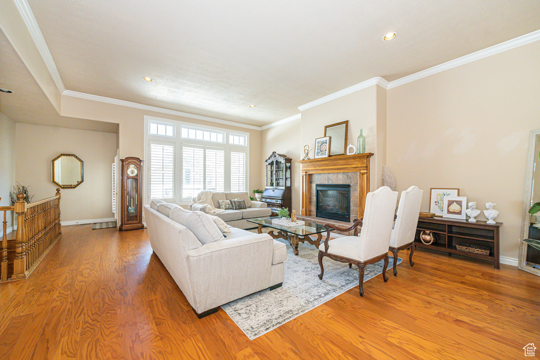 Living room with a tile fireplace, light wood-type flooring, and crown molding