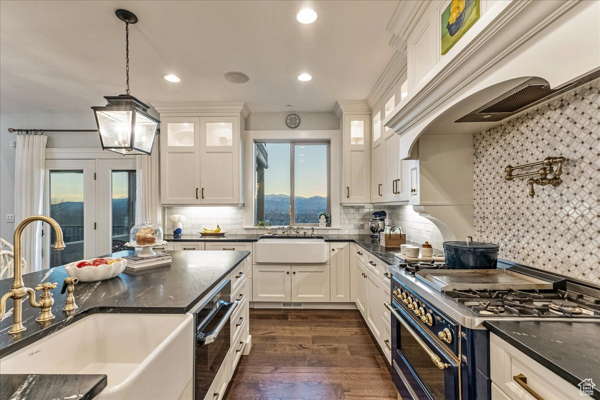 Kitchen featuring backsplash, range with two ovens, sink, and pendant lighting