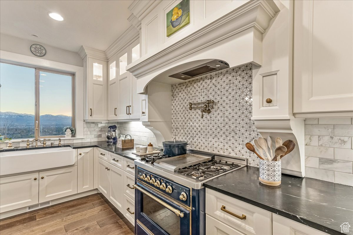 Kitchen featuring backsplash, double oven range, engineered hardwood flooring, and white cabinets