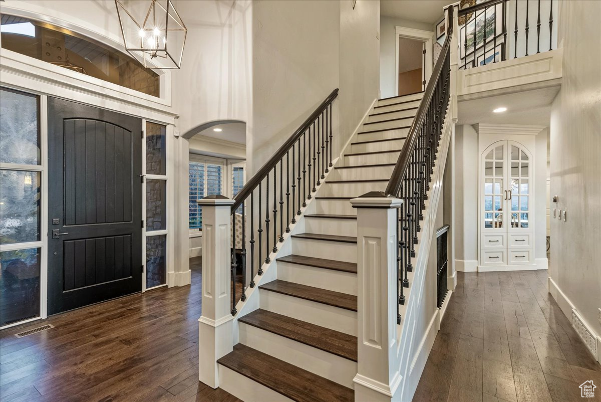 Entryway with engineered hardwood flooring, a notable chandelier, and a towering ceiling