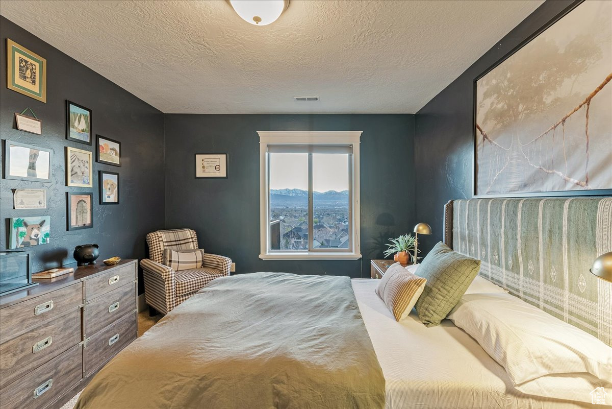 Bedroom with a mountain view and a textured ceiling